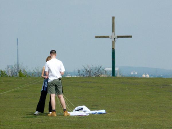 Blick auf 2 Personen, die auf der Halde Pattberg stehen. Im Hintergrund ein Kreuz.