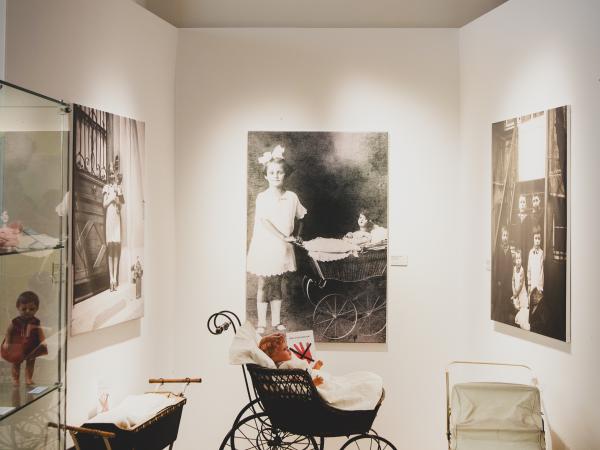 Blick in einen Ausstellungsraum mit Fotos an den Wänden und verschiedenen Kinderwagen