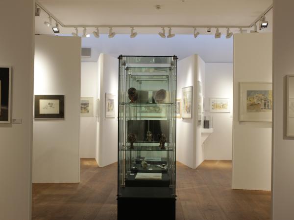 Blick in den Neubau der Ausstellung mit Glasvitrine und Bildern an den Wänden