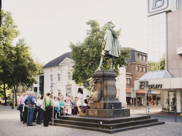 Eine Gruppe von Personen steht vor dem Denkmal von König Friedrich dem ersten.