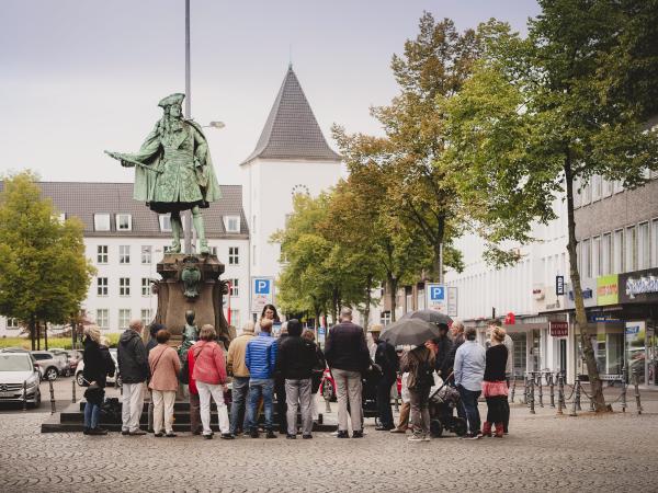 Eine Gruppe steht an einem Denkmal am Altmarkt.