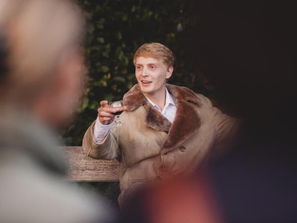 Ein Mann mit dickem Mantel und einem Gals Alkohol in der Hand.
