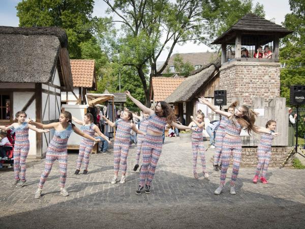 10 Kinder in dem gleichen Outfit Tanzen im Musenhof.