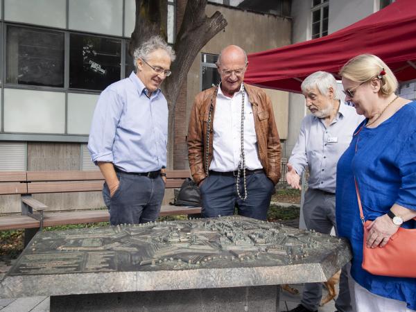 Vier Personen sehen sich das Bronzerelief der Stadt an.