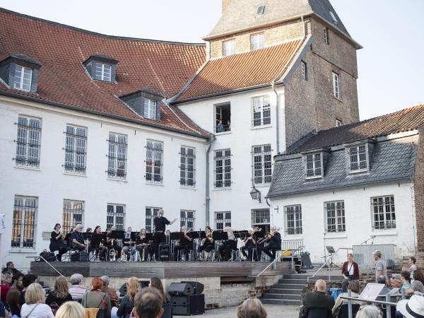 Ein Orchester auf einer Bühne vor dem Moerser Schloss.