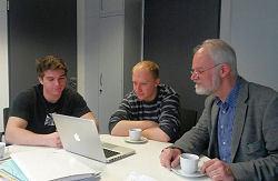 Die beiden Studenten Marc Macziejek (links) und Holger Lieske (Mitte) sitzen mit Thomas Nolte, Lehrer am Adolfinum, an einem Tisch.