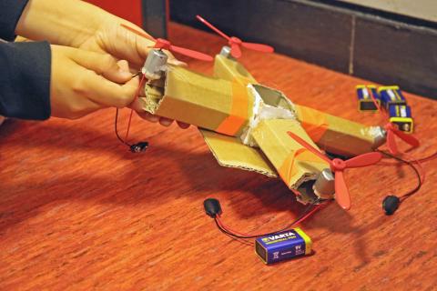 Hände bauen eine Drohne aus Pappe.